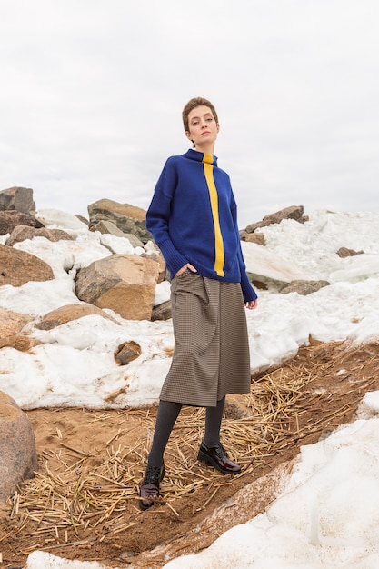 model posing in a stylish blue sweater and divided skirt with her hands in the pockets