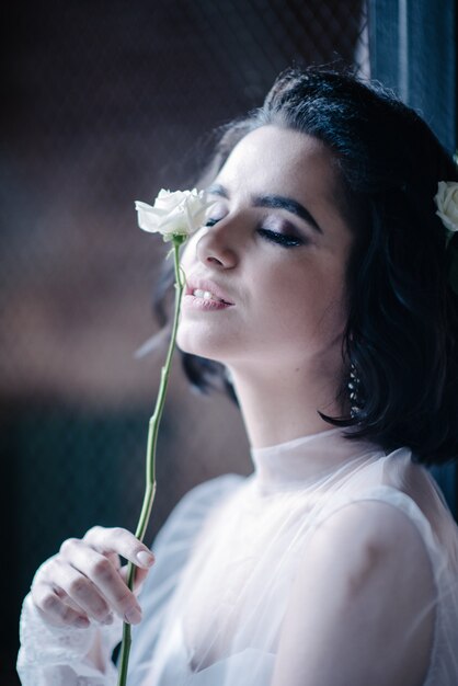 Model posing in a white wedding dress holds a flower in her hand