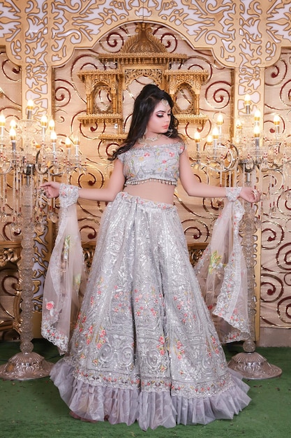 A model in a silver lehenga with a floral design on the top.