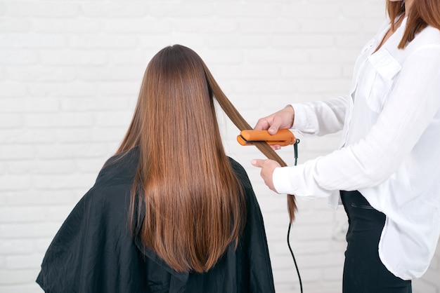 Model sitting while hairstyling in beaty salon with white brick walls.