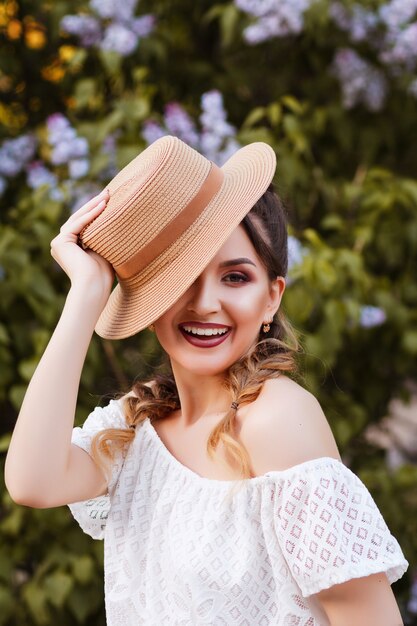 model smiling and holding hat in her hands. in the park in summer. blurred