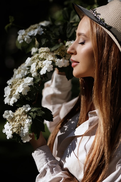 Model sniffs white flowers in summer