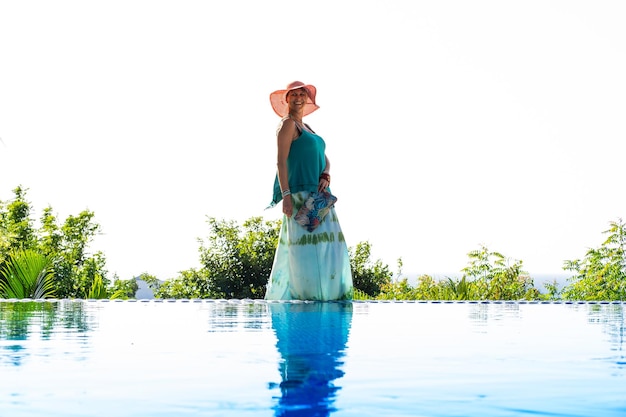 Foto modello in piedi sul bordo di una piscina tropicale all'aperto