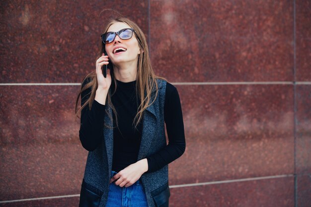 The model stands against the wall talking on the phone