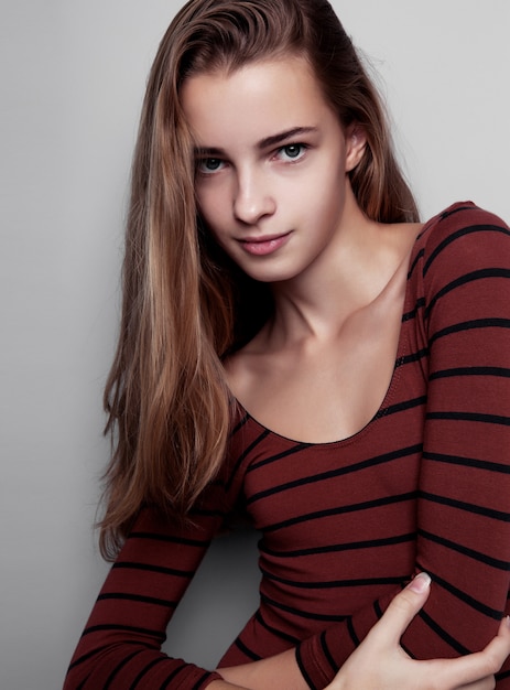 Model test with young beautiful fashion model wearing red body with stripes in studio. Color portrait