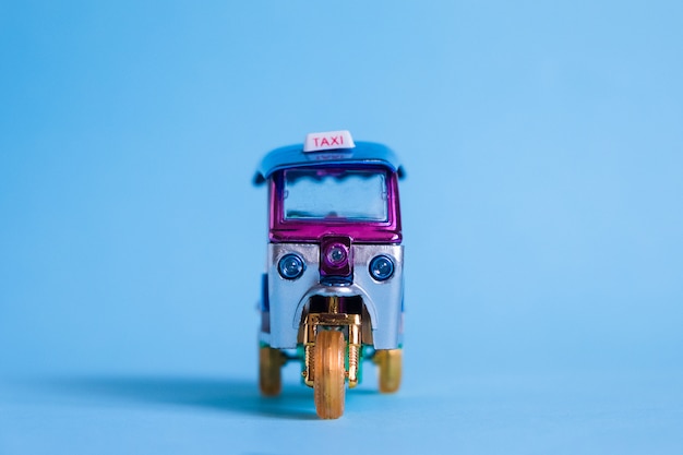 Model Toy tuk tuk isolated on blue wall. Thai traditional taxi in Bangkok Thailand. Souvenir