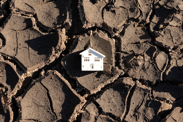 Model van een huis en gebarsten aarde die de verwoesting na een aardbeving weergeeft Plaats voor tekst