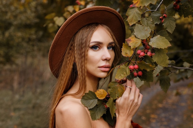 Model with autumn makeup near the mountain ash in October. autumn trends. beauty and fashion