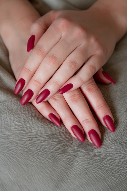 Model woman showing red shellac manicure on long nails