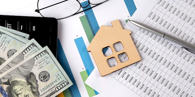 Model wooden house and dollar banknote with calculator and glasses