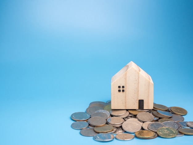 A model wooden house and a pile of coins on blue