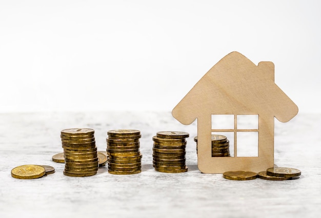 Модель деревянного дома рядом с кучей золотых монет Концепция покупки дома ипотечного кредита