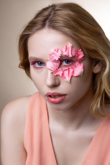 Model working. Appealing professional model with pink eyeshades working while showing poses with petals on face