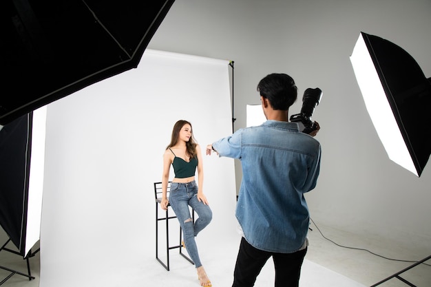 Фото Модель молодая женщина позирует для фото, сделанного профессиональным фотографом в студии по концепции моды фотограф и модель молодой человек фотографирует фотомодель
