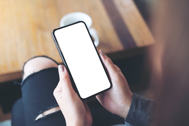 Modelbeeld van de hand die van de vrouw zwarte mobiele telefoon met het lege witte desktopscherm houden