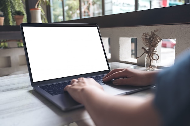 Modelbeeld van een vrouw die en bij laptop met het lege witte Desktopscherm op lijst in koffie typen typen