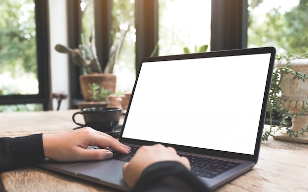 Foto modelbeeld van een vrouw die en op laptop met het lege witte desktopscherm met koffiekop gebruiken typen op houten lijst in koffie