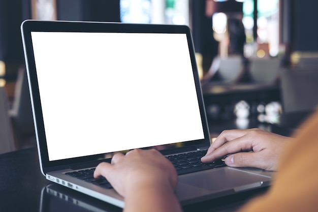 Modelbeeld van een vrouw die laptop met het lege witte scherm op lijst in moderne koffie met behulp van