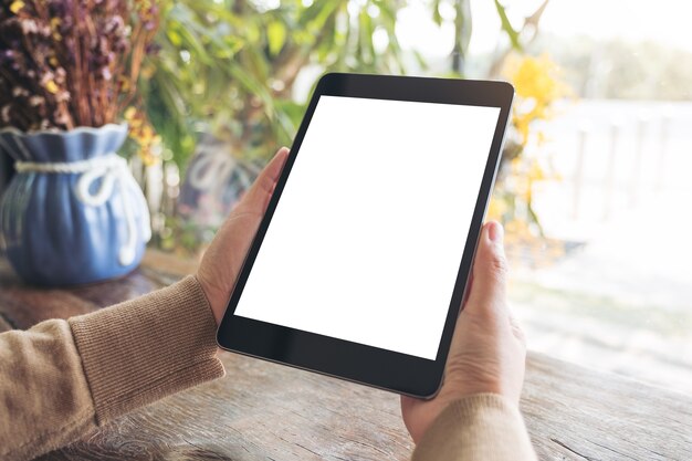 Modelbeeld van een vrouw die zwarte tabletpc met het lege witte Desktopscherm in koffie houden