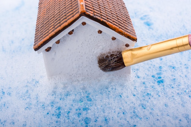 Modelhuis en schilder penseel in schuimig water