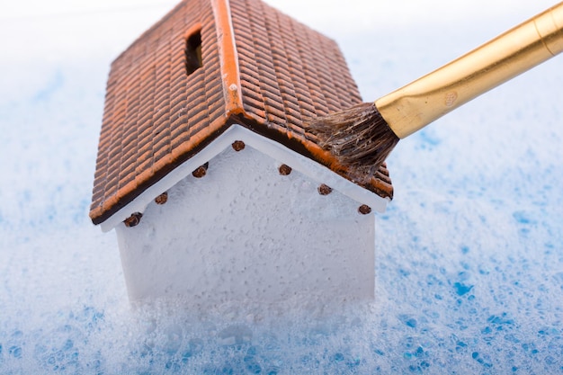 Modelhuis en verfkwast in schuimend water