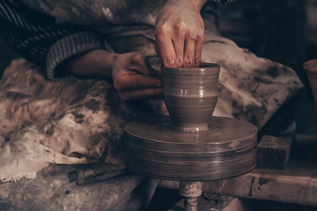 Foto ciotola di modellazione di argilla su ruota in officina di ceramica mani di artigiano stampo stoviglie tecnica di lavorazione dell'argilla