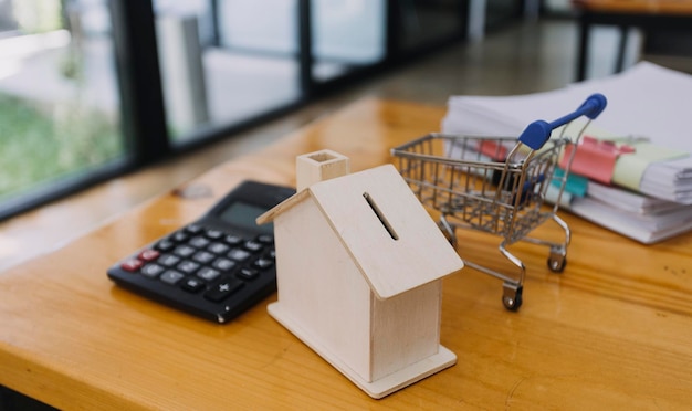 Foto modellering van houten huizen en munten en dollars op houten tafelsvoorbereidingsconcept voor de aankoop van huismodellen en de snelst groeiende vastgoedeconomie verhuizen naar huis of huren van onroerend goed via agentxa