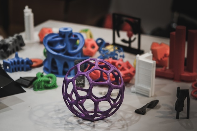 Photo models printed by 3d printer. dark. copy space. bright colorful objects printed on a 3d printer on a table. modern additive technologies 4.0 industrial revolution