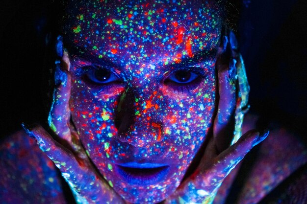 Modelvrouw in neonlicht mooi modelmeisje met het ontwerp van de fluorescerende make-upkunst van discodanseres die in uv-licht kleurrijke make-up Nachtclubpartij dansen