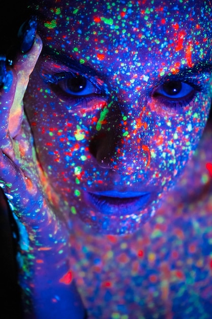 Modelvrouw in neonlicht mooi modelmeisje met het ontwerp van de fluorescerende make-upkunst van discodanseres die in uv-licht kleurrijke make-up Nachtclubpartij dansen
