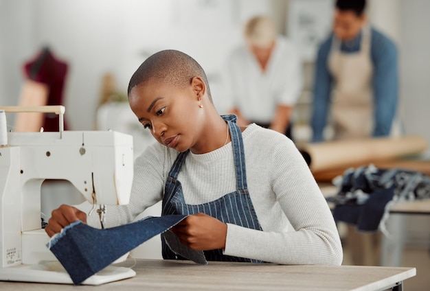 Modeontwerp en creatief werk in een workshop Jonge Afro-Amerikaanse fabrieksarbeider naait nieuwe trendy modieuze kleding van het seizoen Zwarte vrouw die op een machine werkt op een drukke werkplek