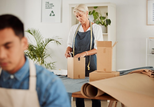 Foto modeontwerp en stijl met een kleermaker of een creatieve ontwerper die dozen inpakt voor verzending en levering vrouwelijke stylist bereidt een doos voor om een bestelling in haar studio of atelier te voltooien