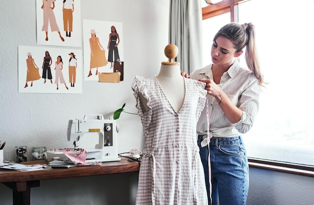 Modeontwerp en vrouw met mannequin meetlint en naaimachine bij creatief klein bedrijf Focus creativiteit en kleermaker met jurk op pop voor kledingontwerper in textielopstartstudio