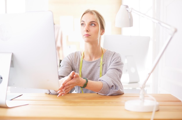 Modeontwerper vrouw die in de studio aan het bureau werkt