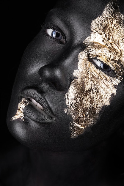 Modeportret van een donkerhuidig meisje met gouden make-up