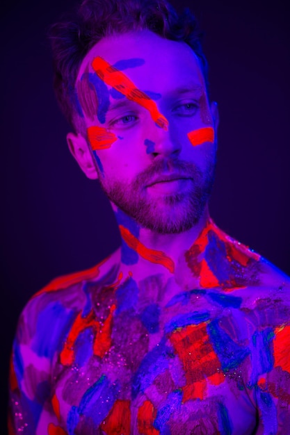 Modeportret van een man met ultraviolette verf op zijn lichaam en neonlicht in cyberpunkstijl