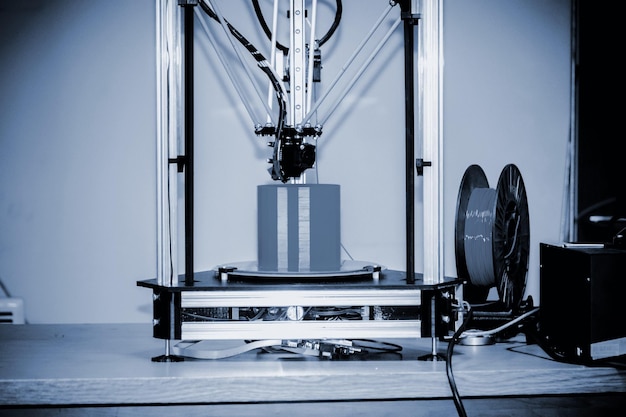 現代の3Dプリンター印刷図のクローズアップ。スペースをコピーします。自動3次元3Dプリンターは、実験室でプラモデルを実行します。進歩的な現代の添加剤技術。ブルーグレーカラー