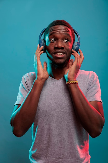 Modern adult being shocked after hearing song on headphones. Young person listening to online radio music on wireless earphones and having surprised reaction, enjoying record play.