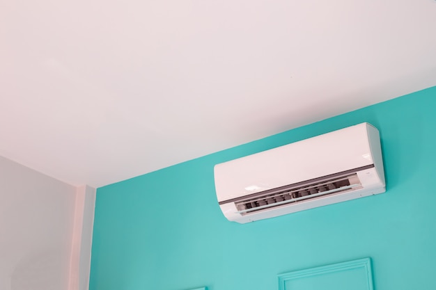 Modern air conditioner on blue wall in bedroom at home, nobody.