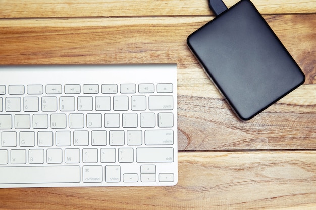 Modern aluminum computer keyboard of a laptop and Hard disk on the desk office wood. technology Electronic Devices. Top view. Hdd