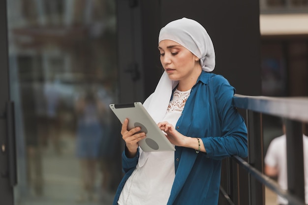 Donna musulmana araba moderna con computer tablet all'aperto