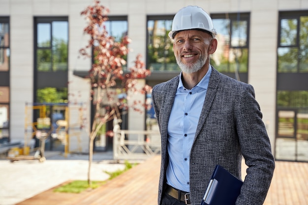 Foto architetto moderno di successo di mezza età uomo d'affari ingegnere manager che indossa il casco guardando