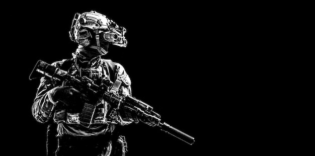 Modern army special forces equipped soldier, anti terrorist squad fighter, elite mercenary armed assault rifle, standing in darkness with night vision goggles on helmet, studio portrait, copyspace