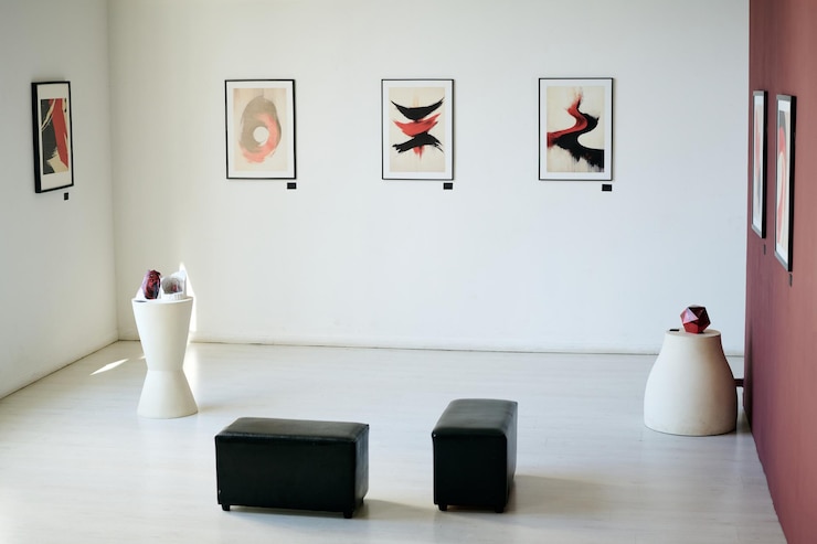Photo 暗い家具や刻が付いた白い壁に抽象的な絵画を展示するモダンアートギャラリー
