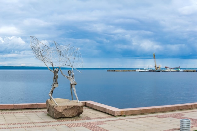 페트로자보드스크 카리아의 기<unk>을 배경으로 해변에 있는 조각가 라파엘 콘수에그라 (Rafael Consuegra) 의 현대 미술 물체 조각품 '어부들'