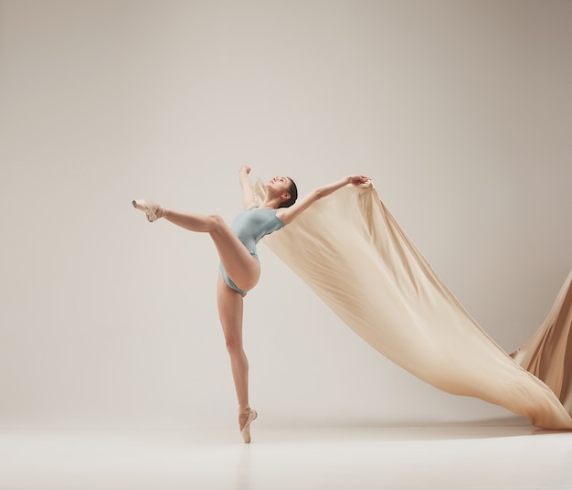 Modern ballet dancer exercising in full body on white studio background. Ballerina or female dancer with silk fabric dancing on white studio background. Caucasian model on pointe shoes