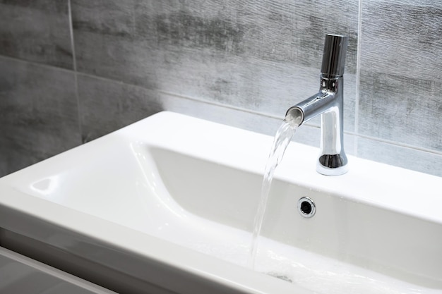 Modern bathroom faucet Flowing water from water tap copy space