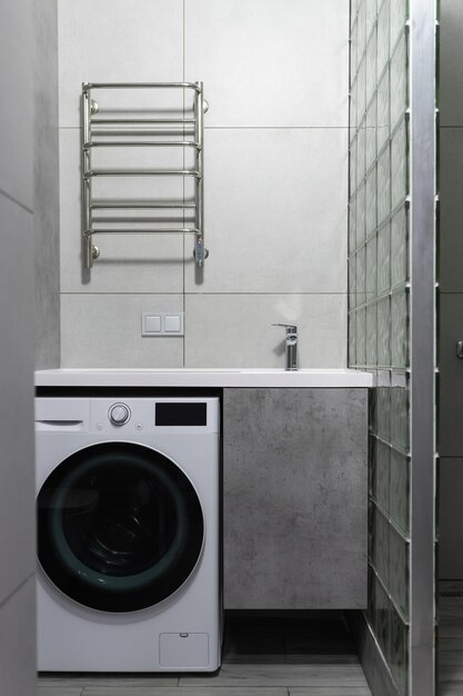 Modern bathroom interior with minimalist lighting Washing machine sink with cabinet and towel dryer