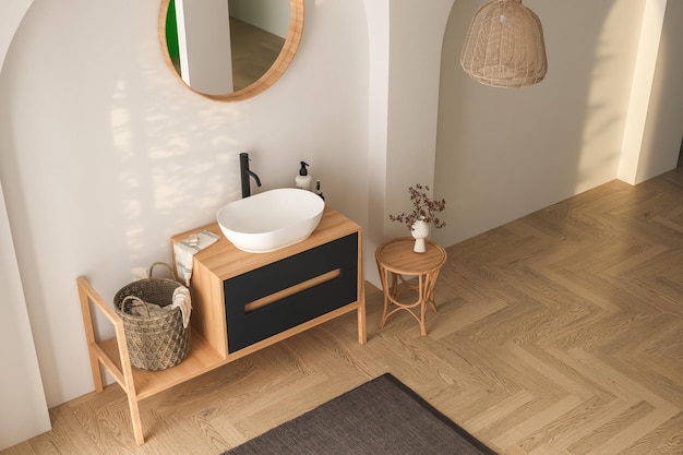 Modern bathroom interior with white walls, white sink with oval mirror, bathtub and parquet floor