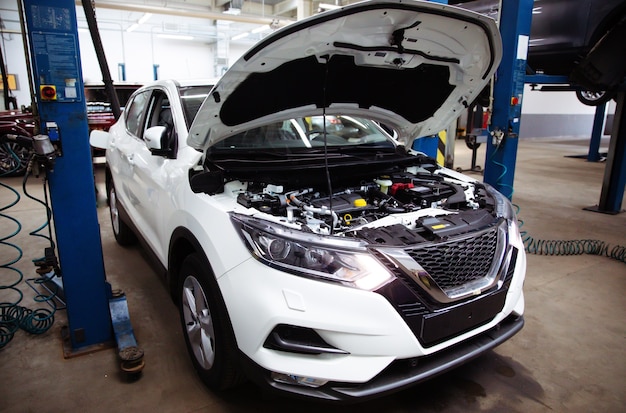 Modern beautiful car with open hood at a service station in the process of being repaired